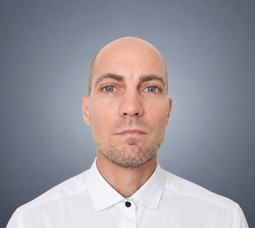 Portrait professionnel de Grégory Mastorgio en chemise blanche sur fond gris bleuté.